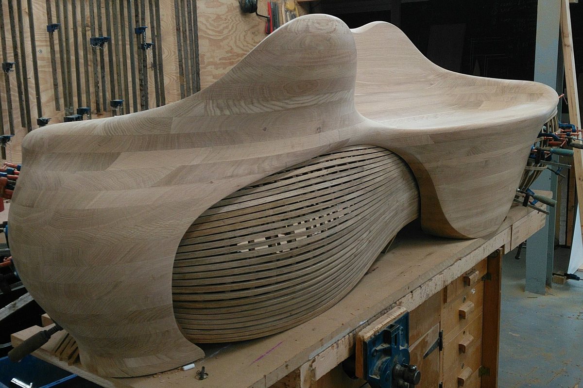 A carved lounger, its slatted flank curving in beneath the seat