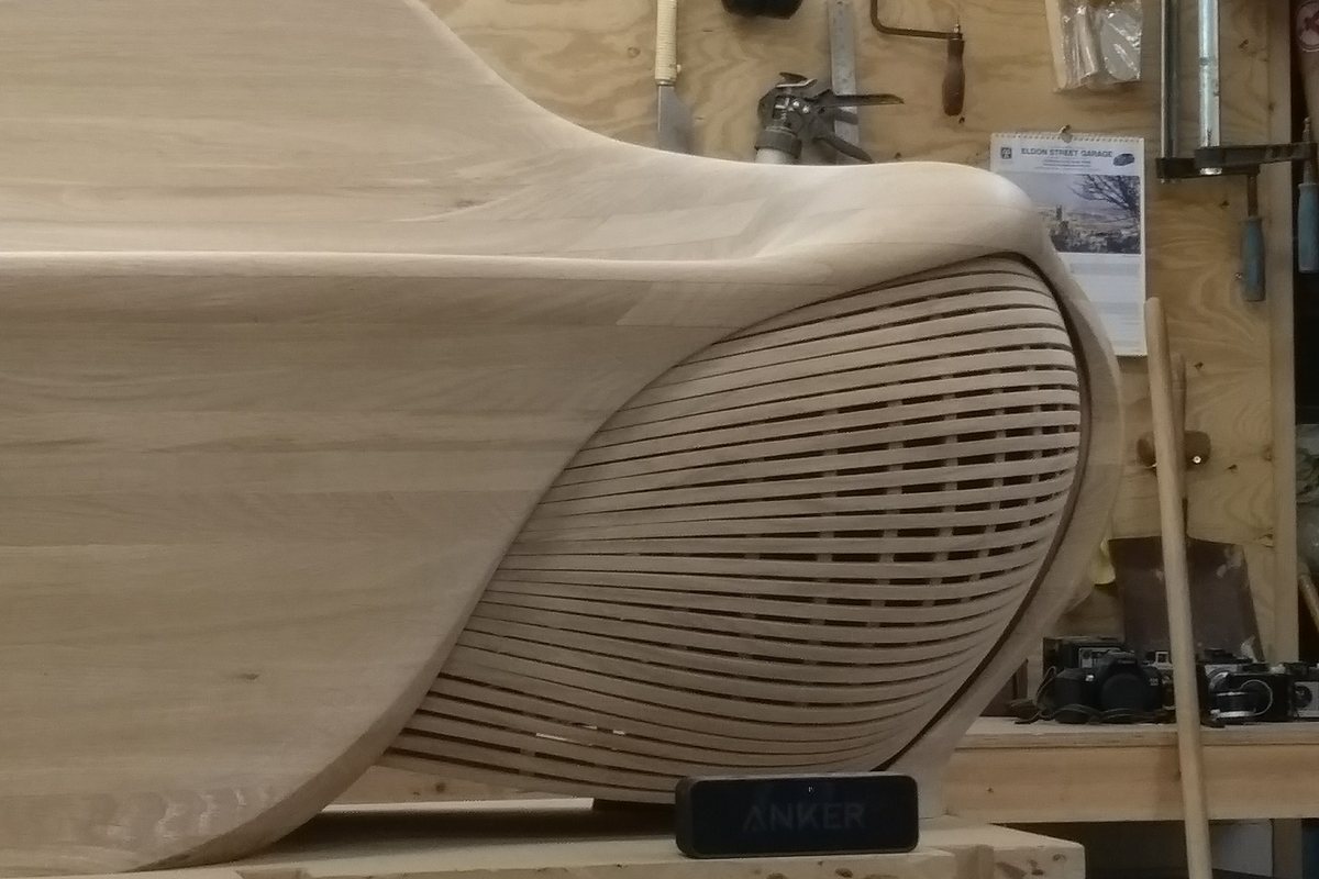 A carved lounger, its slatted flank curving in beneath the seat