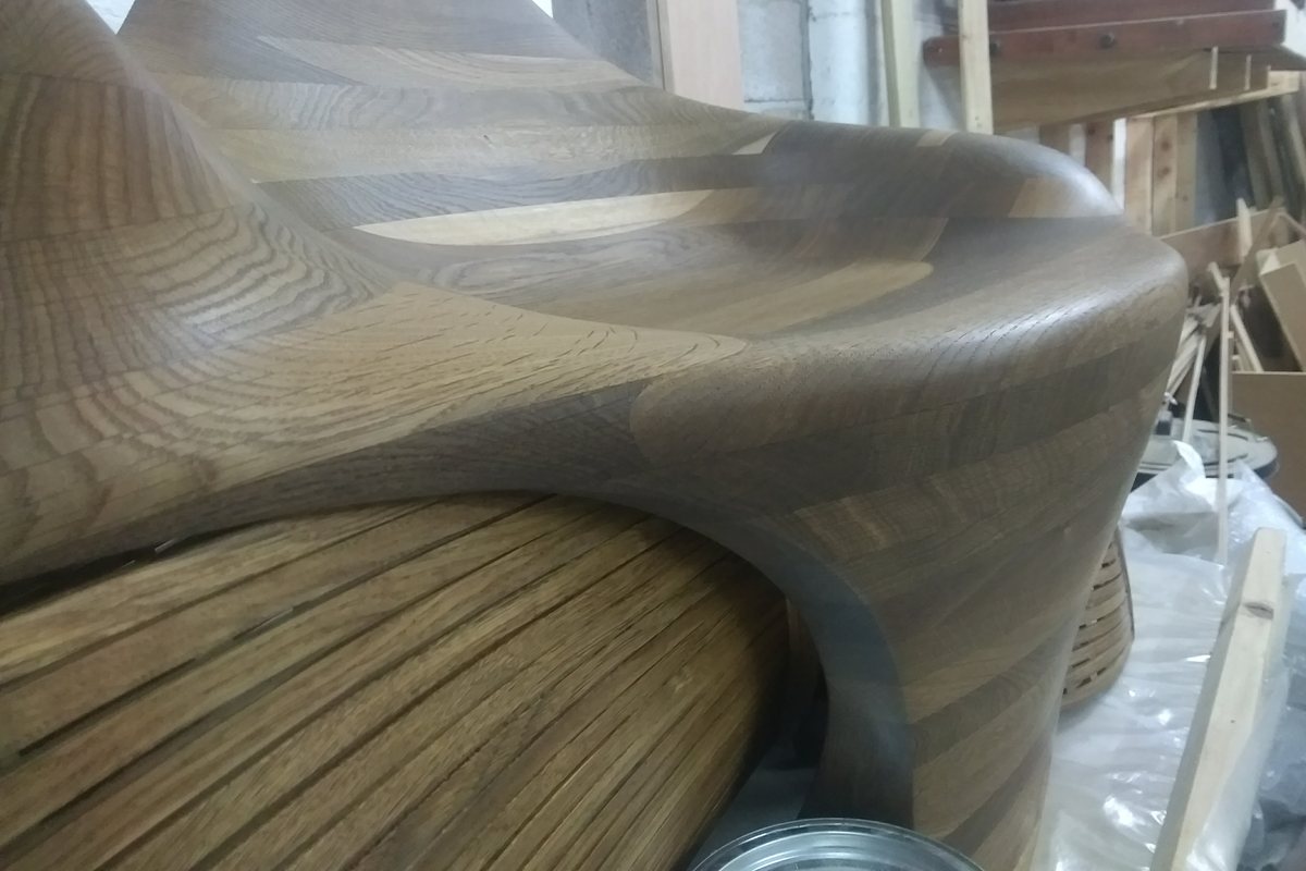 A carved lounger, its slatted flank curving in beneath the seat