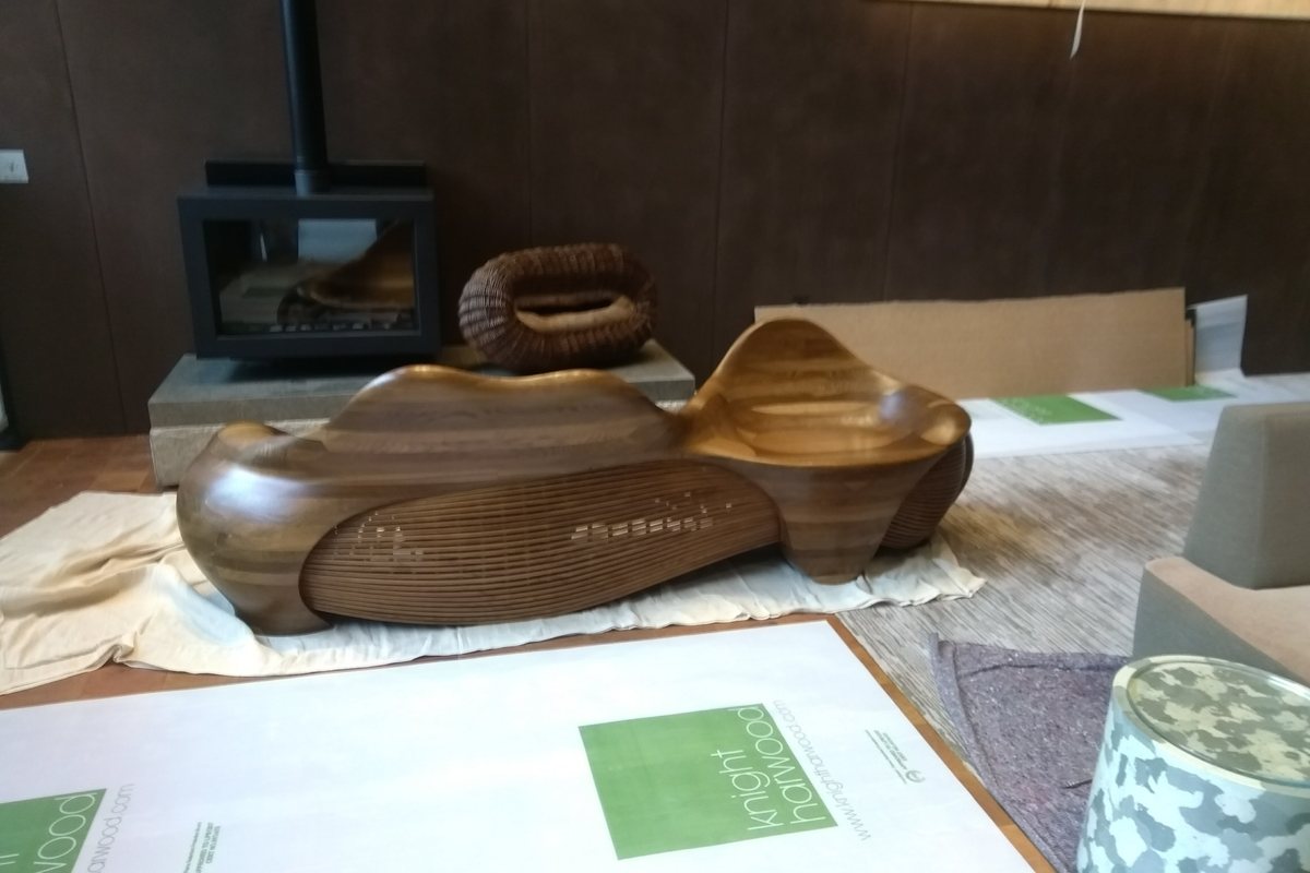 A carved lounger, its slatted flank curving in beneath the seat