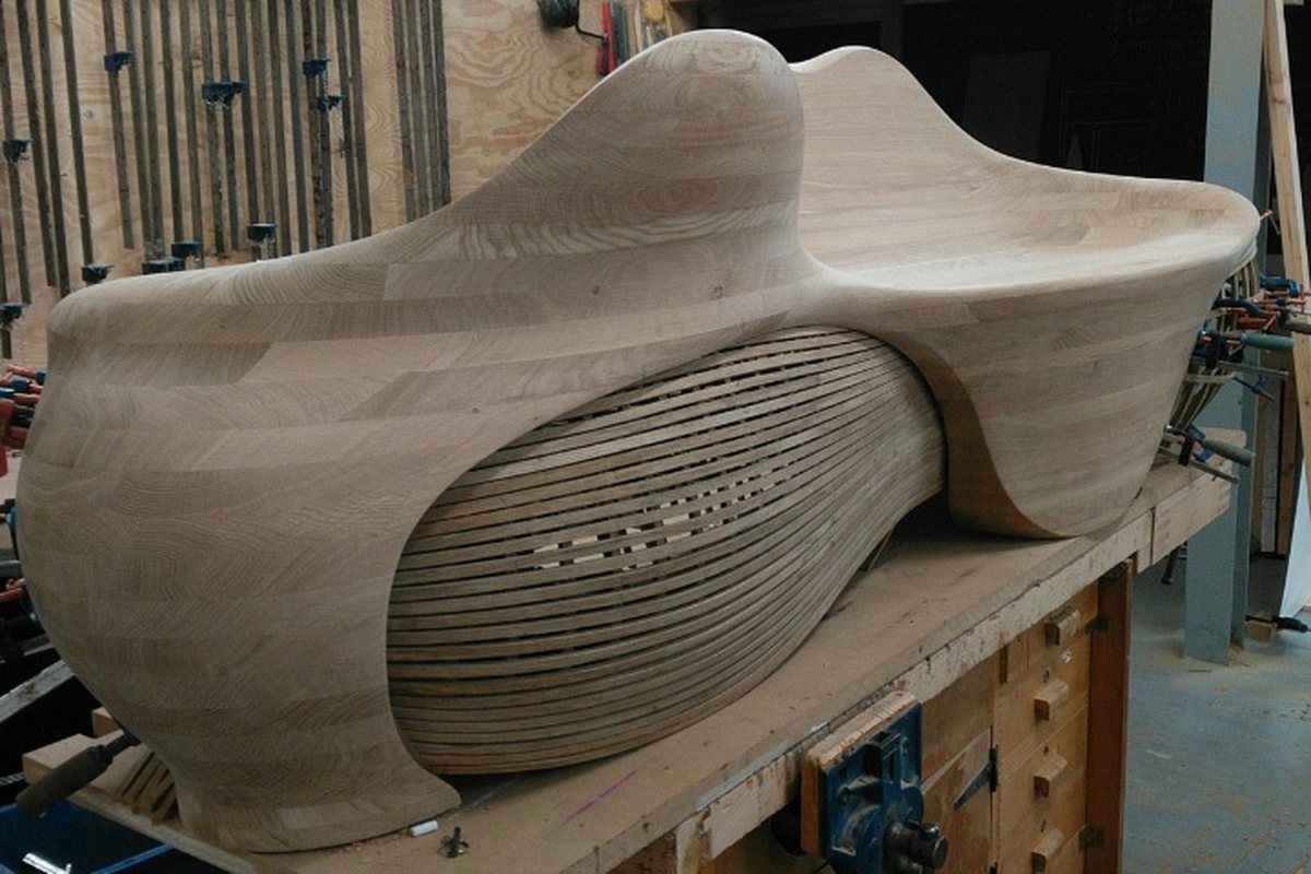 A carved lounger, its slatted flank curving in beneath the seat