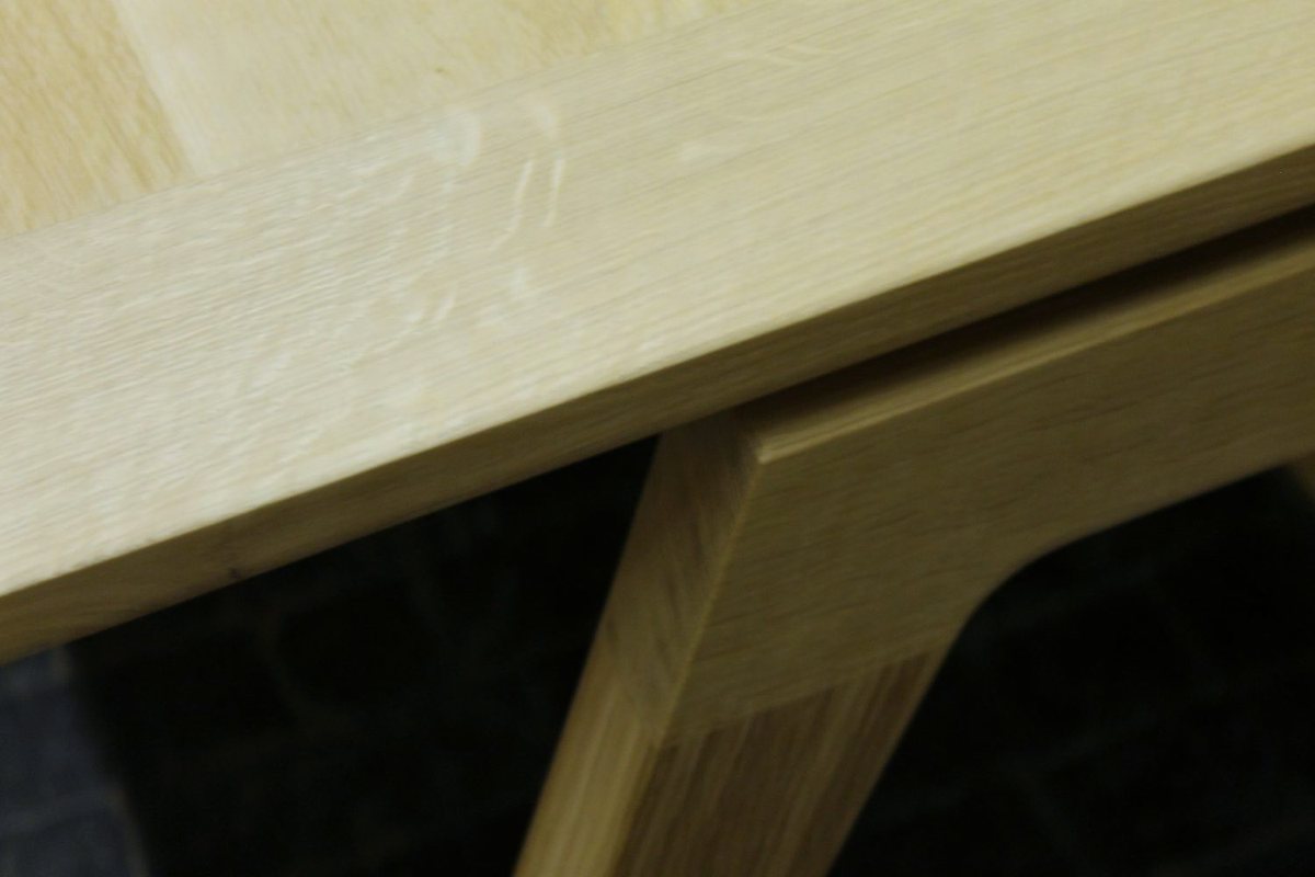 A desk in pale ash, its legs splayed and tapered