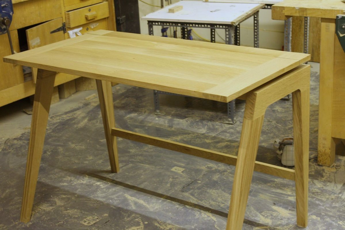 A desk in pale ash, its legs splayed and tapered