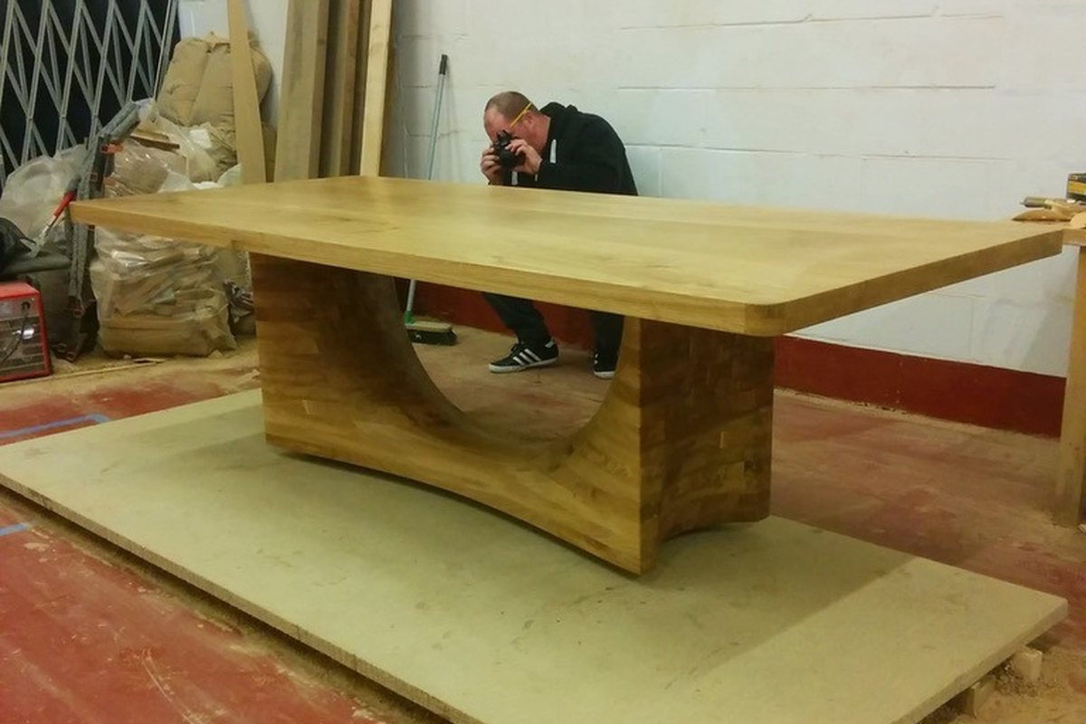 An oak dining table on a deep scooped base, photographed in the workshop