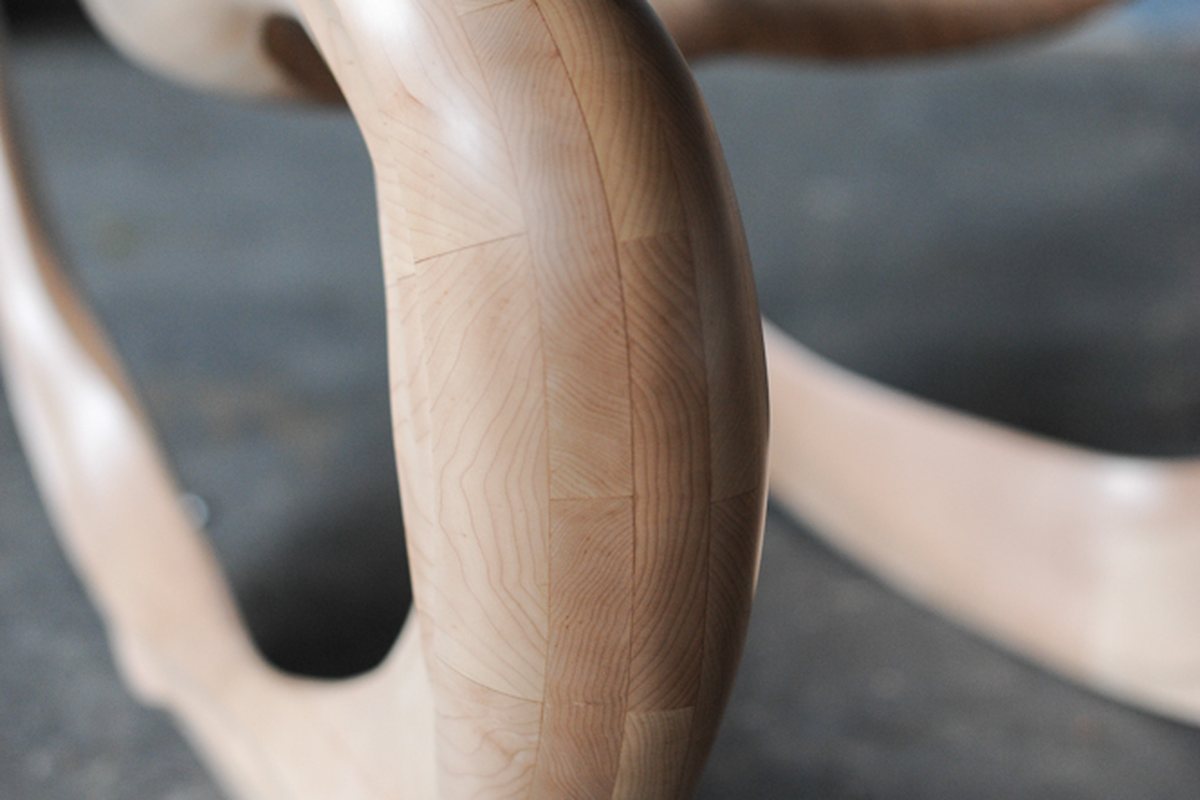 A rocking chair carved in maple, its loops running to the floor
