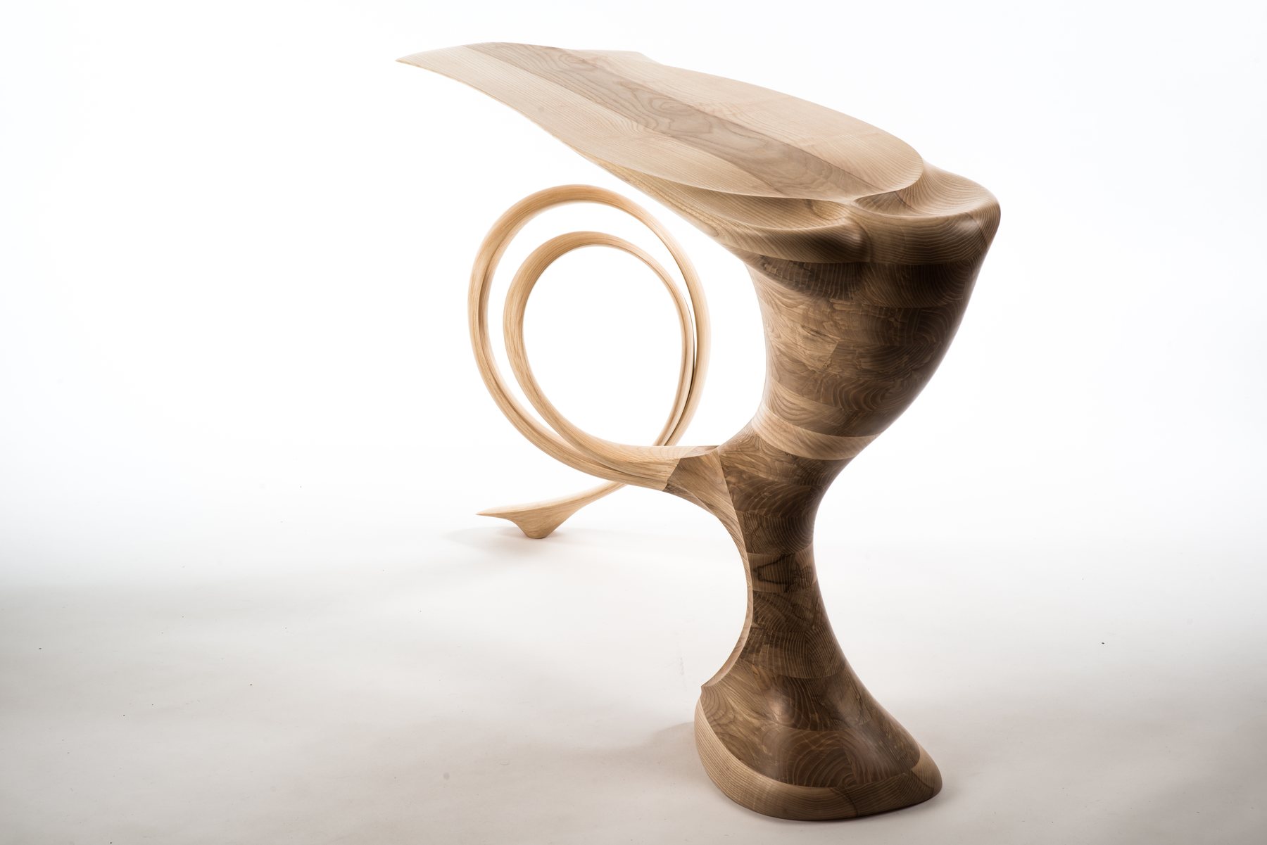 A console table in ash and walnut, its blade of a top carried on a coiled leg.