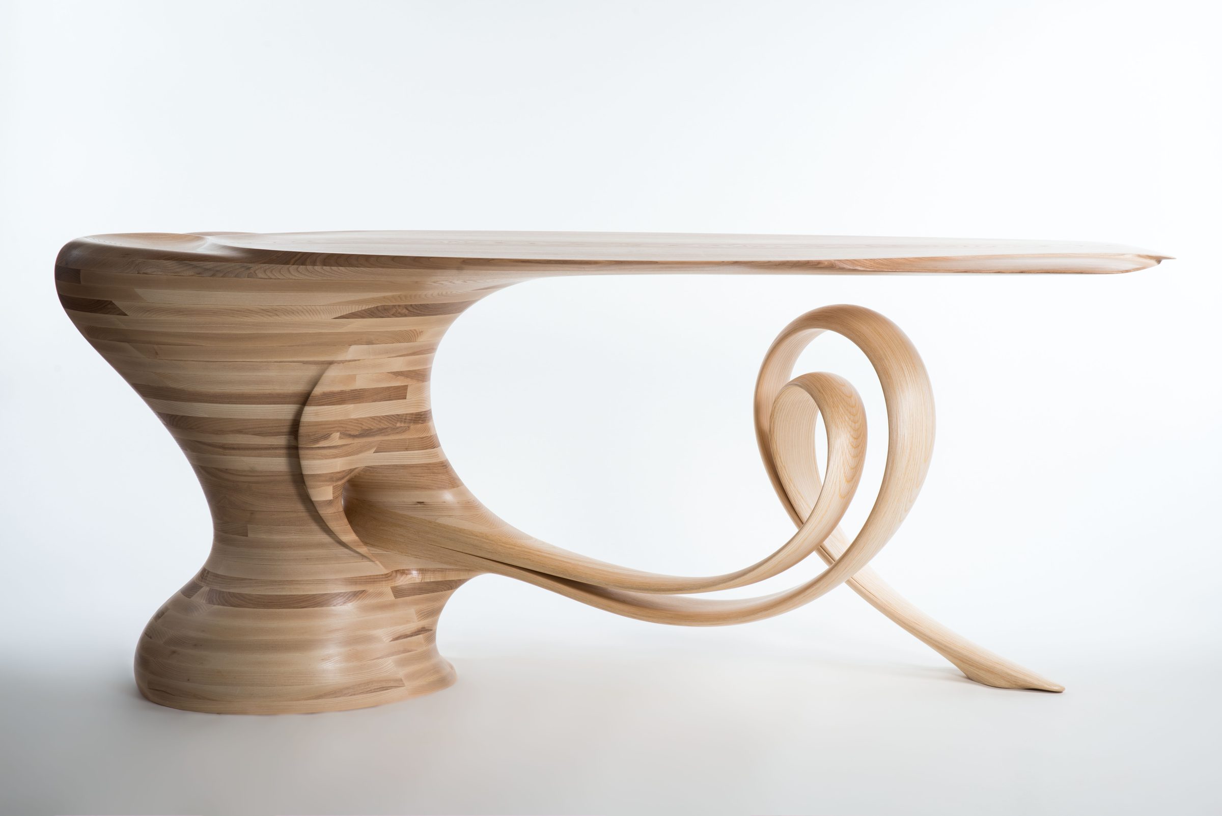 Waiho — a console table in pale ash, its thin cantilevered top carried above a curling ribbon leg.